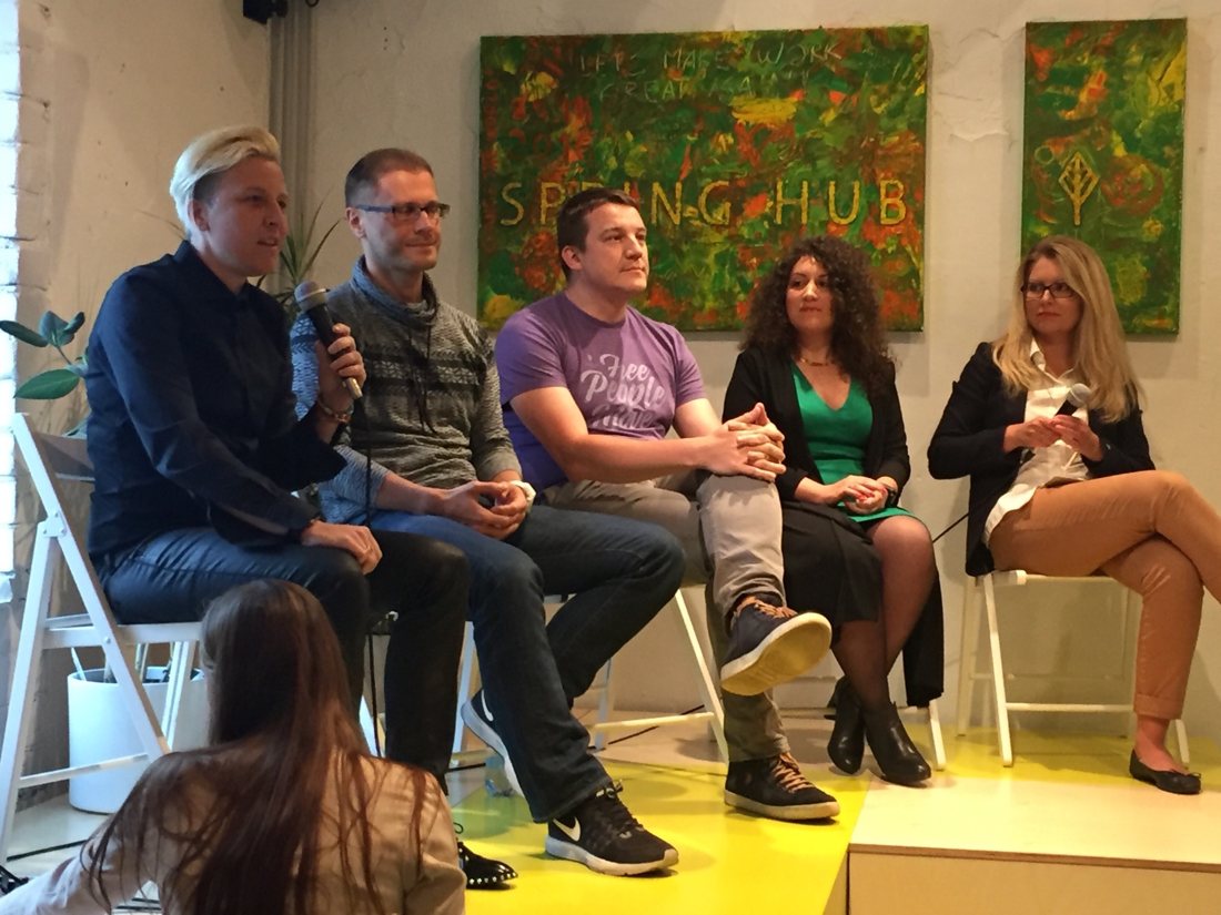 Lauren Proctor speaking into a microphone on a five-person panel at Spring Hub.